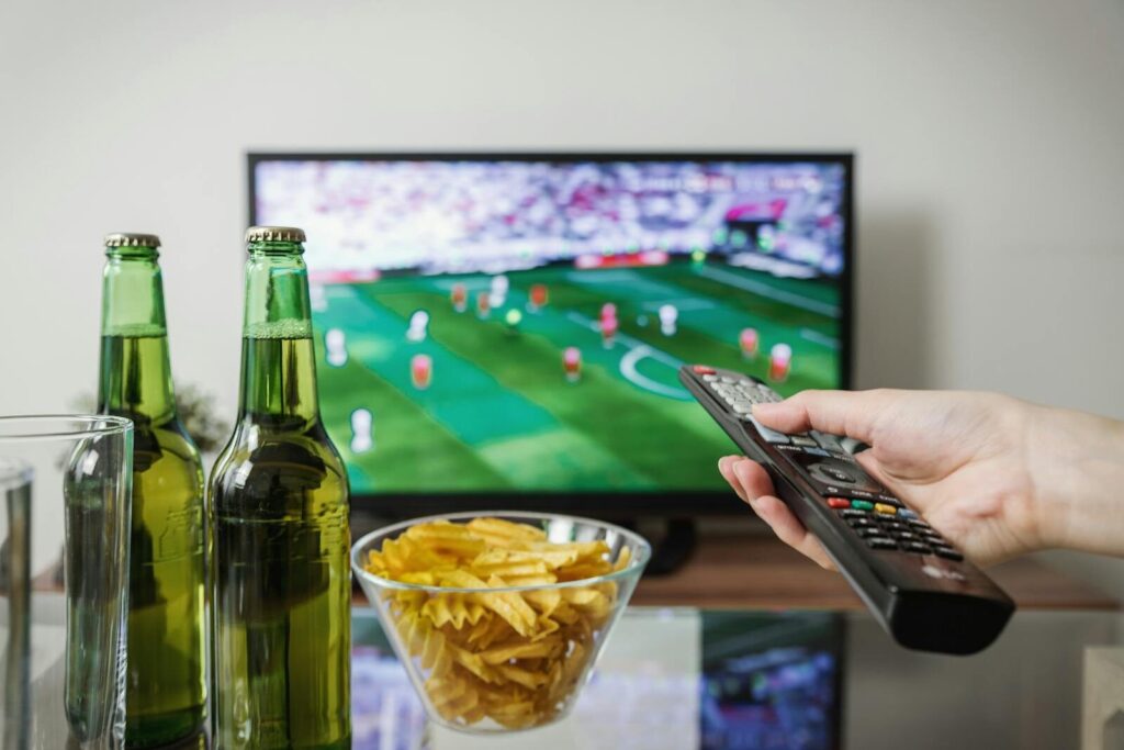 Man holder fjernbetjening og ser VM i fodbold på fjernsyn derhjemme