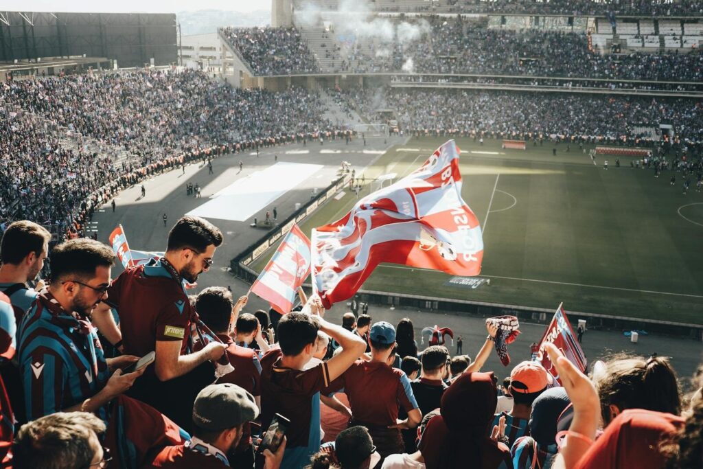 Stor flok mennesker sidder med flag på et fodboldstadion