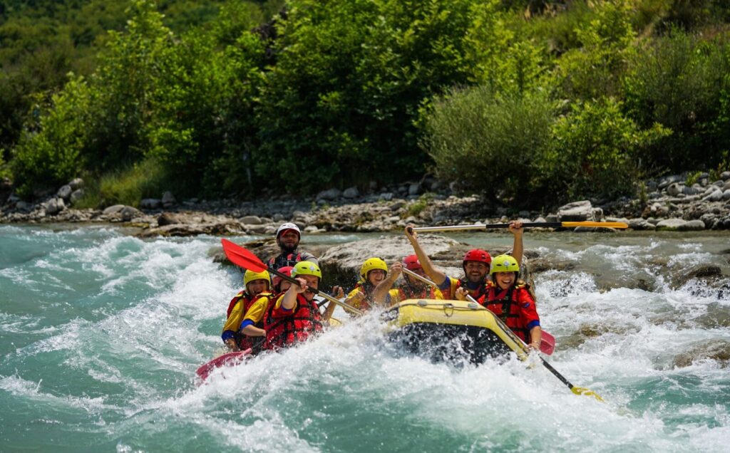 Folk der sejler i en gul båd ned af en flod som riverrafting