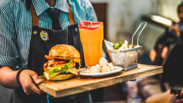 Person med et sabbatårjob i udlandet som tjener, serverer burger med en drink