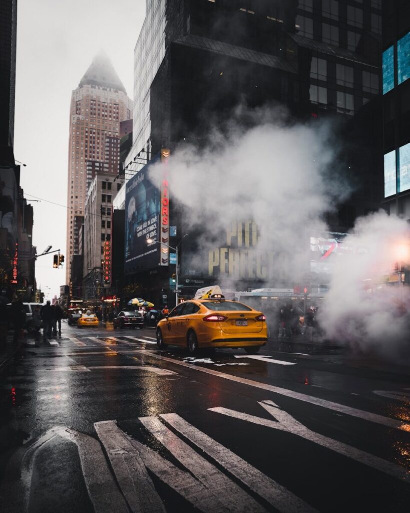 Gul taxa køre gennem gade i new york, USA med skyskrabere på hver side